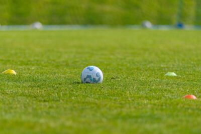 Soccer ball on a vibrant green grass field surrounded by colorful training cones, ideal for sports and recreation themes