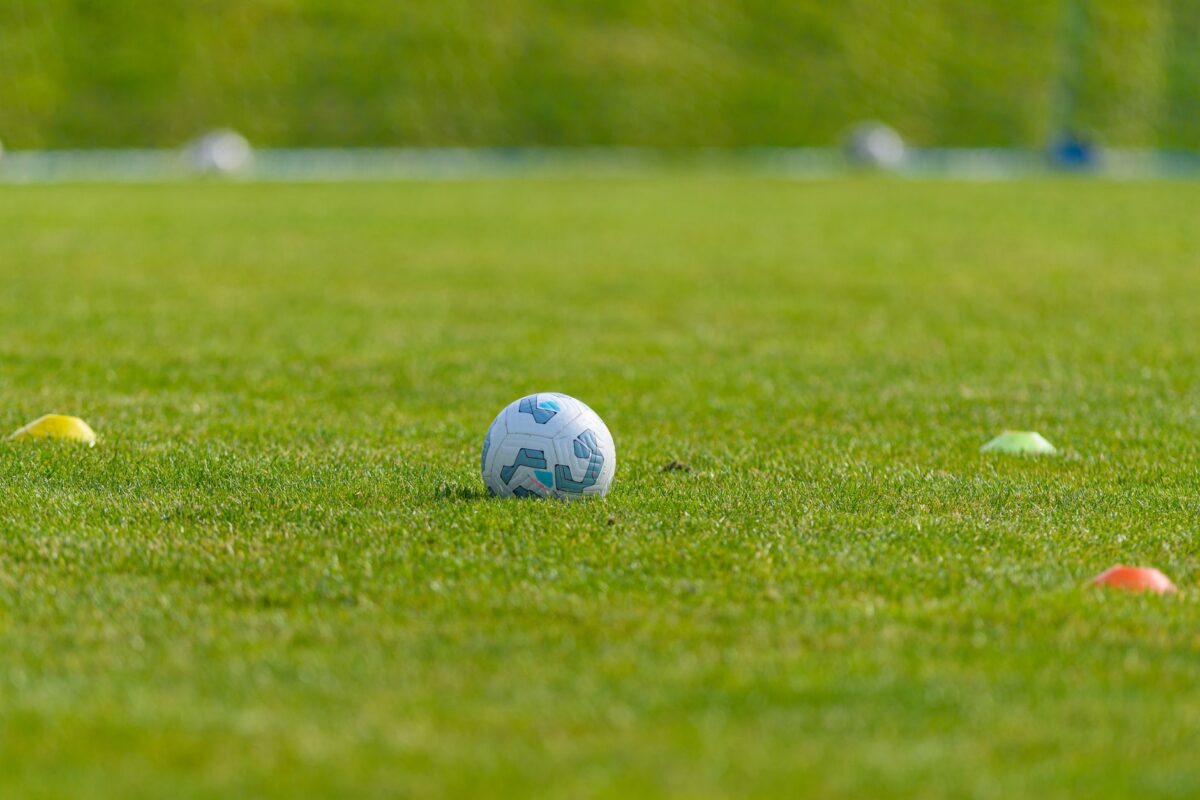 Soccer ball on a vibrant green grass field surrounded by colorful training cones, ideal for sports and recreation themes